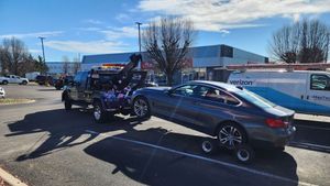 A tow truck is towing a car in a parking lot