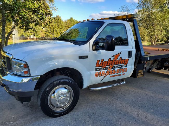 A white tow truck with the word lightning on it