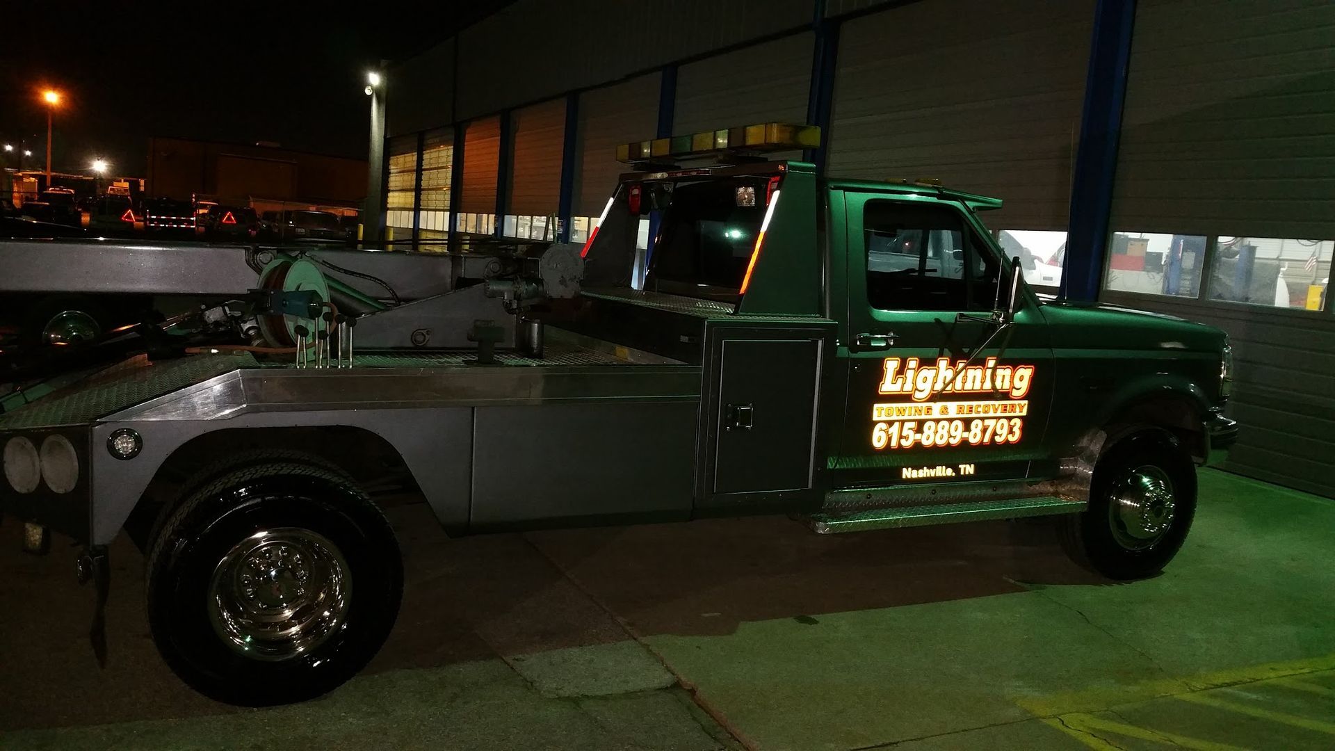 A tow truck is parked in front of a building at night.