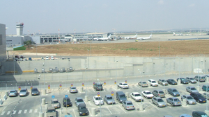 A lot of cars are parked in a parking lot in front of an airport