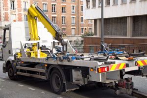 A tow truck with a crane on the back is parked on the side of the road.