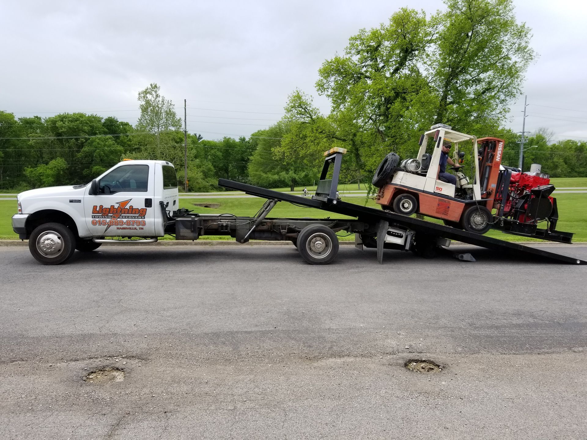 A tow truck with a forklift on the back of it