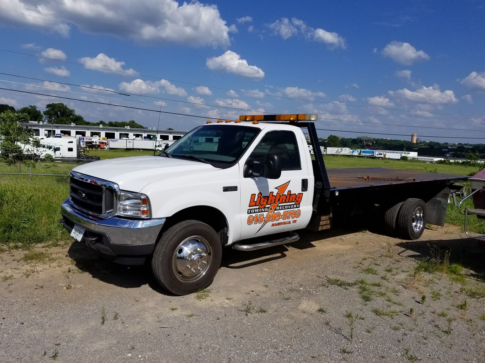 A white tow truck is parked in a dirt lot.