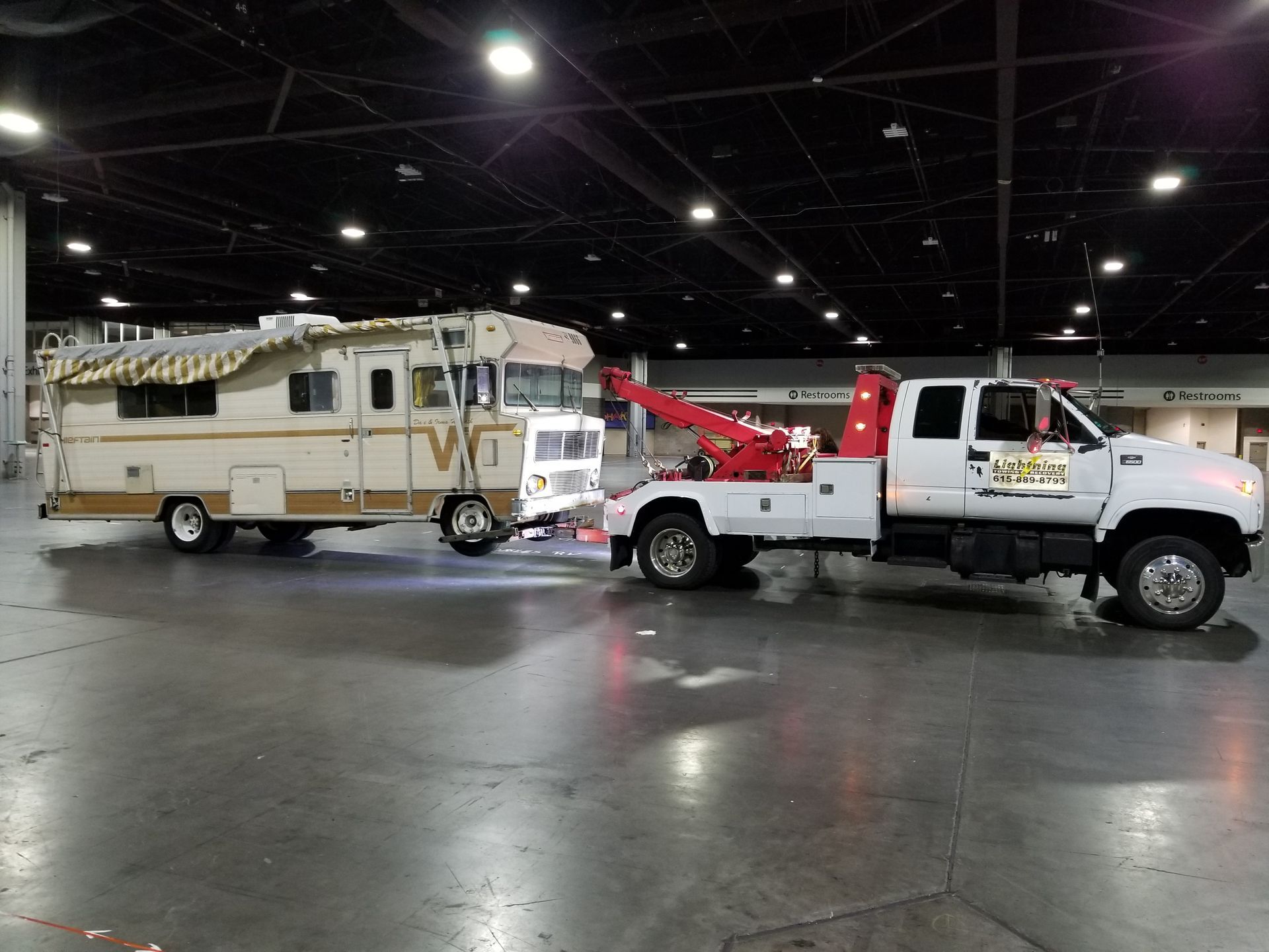 A tow truck is towing a rv in a warehouse.