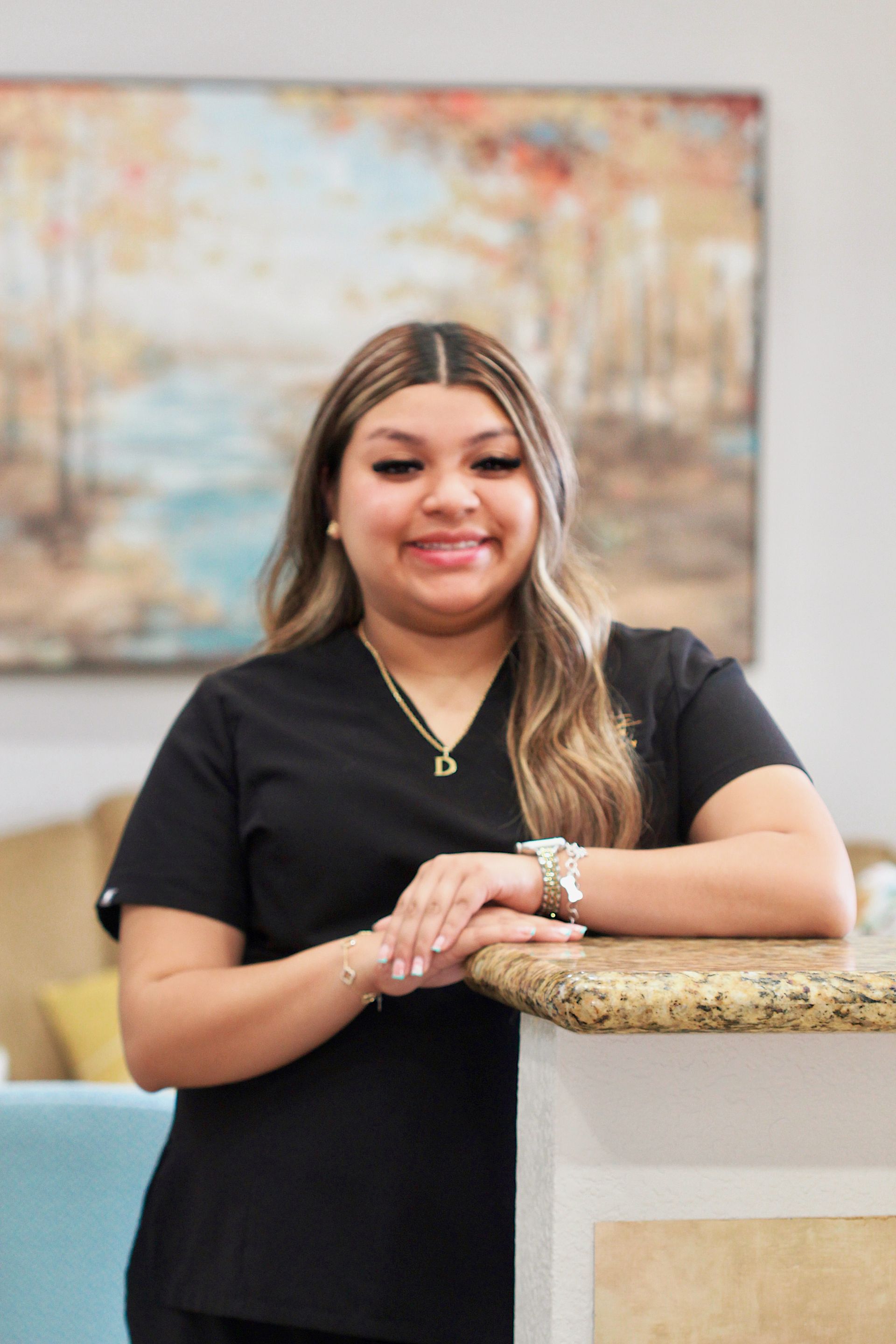 Smiling woman in a black top leaning on a counter in a bright office lobby
