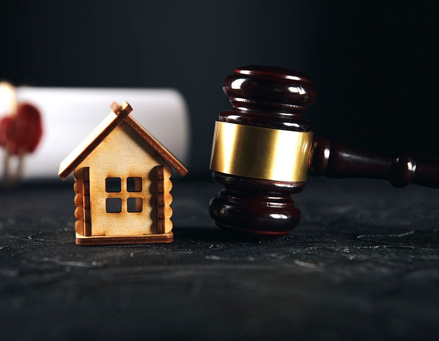 A wooden house is sitting next to a wooden gavel on a table.