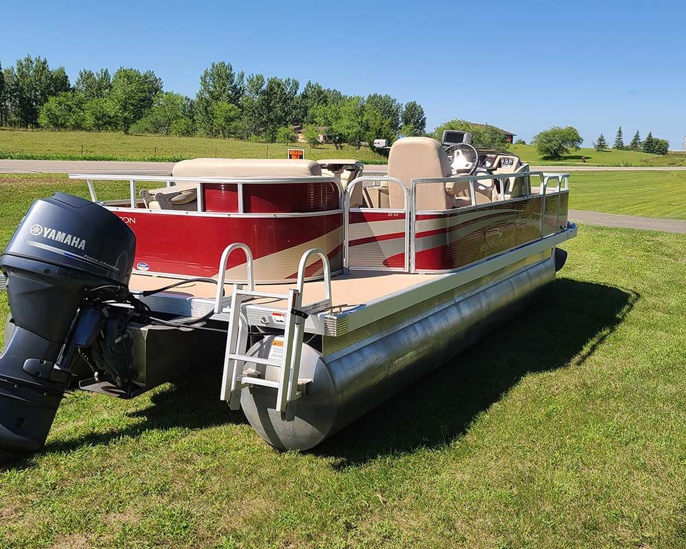 A pontoon boat with a yamaha motor is parked in the grass