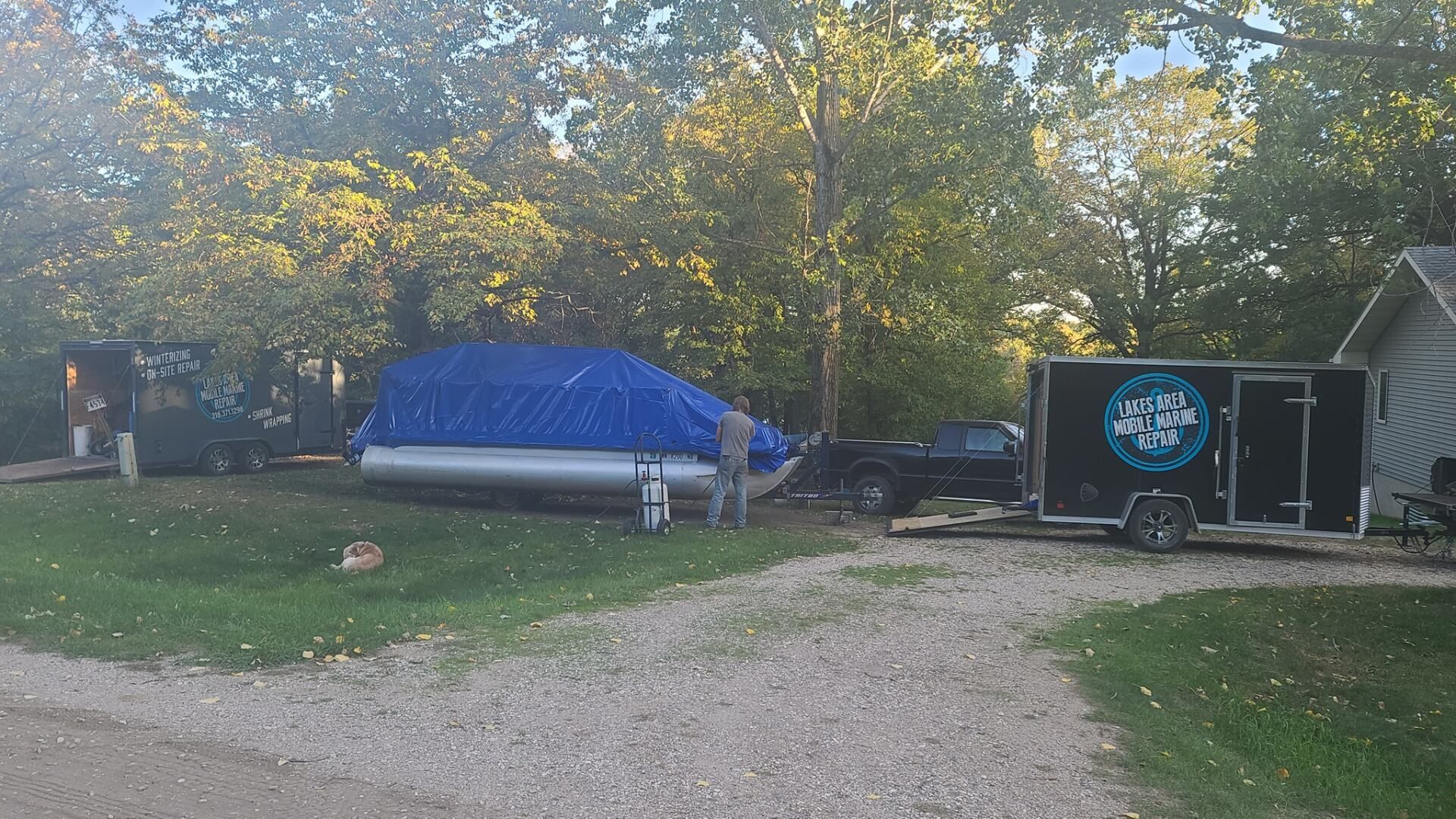 A boat is sitting on top of a trailer in a driveway next to a house.
