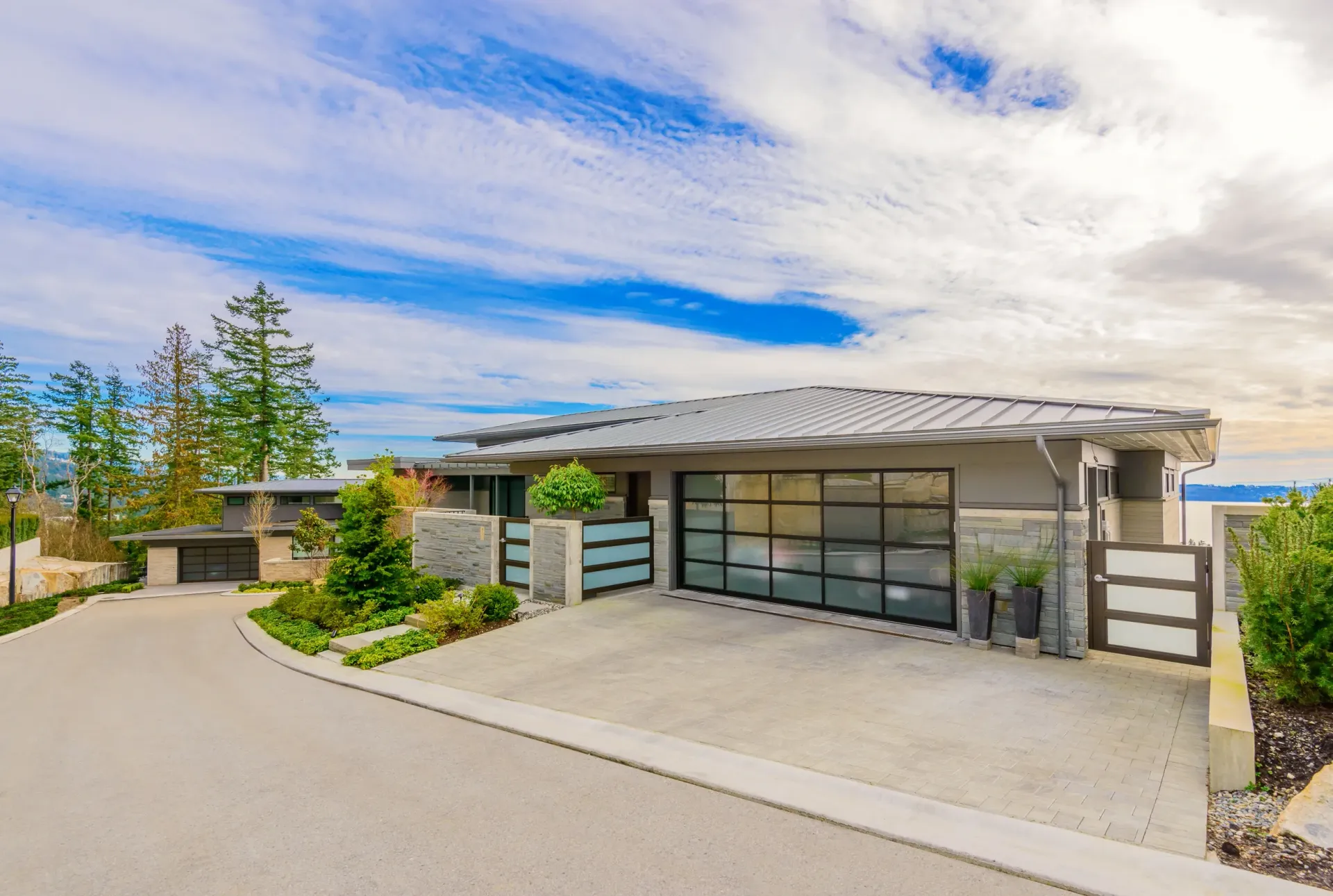 Modern, single-story house with a contemporary glass garage, gray siding, and stone accents, set under a blue sky — Sand & Stone in Worongary, QLD