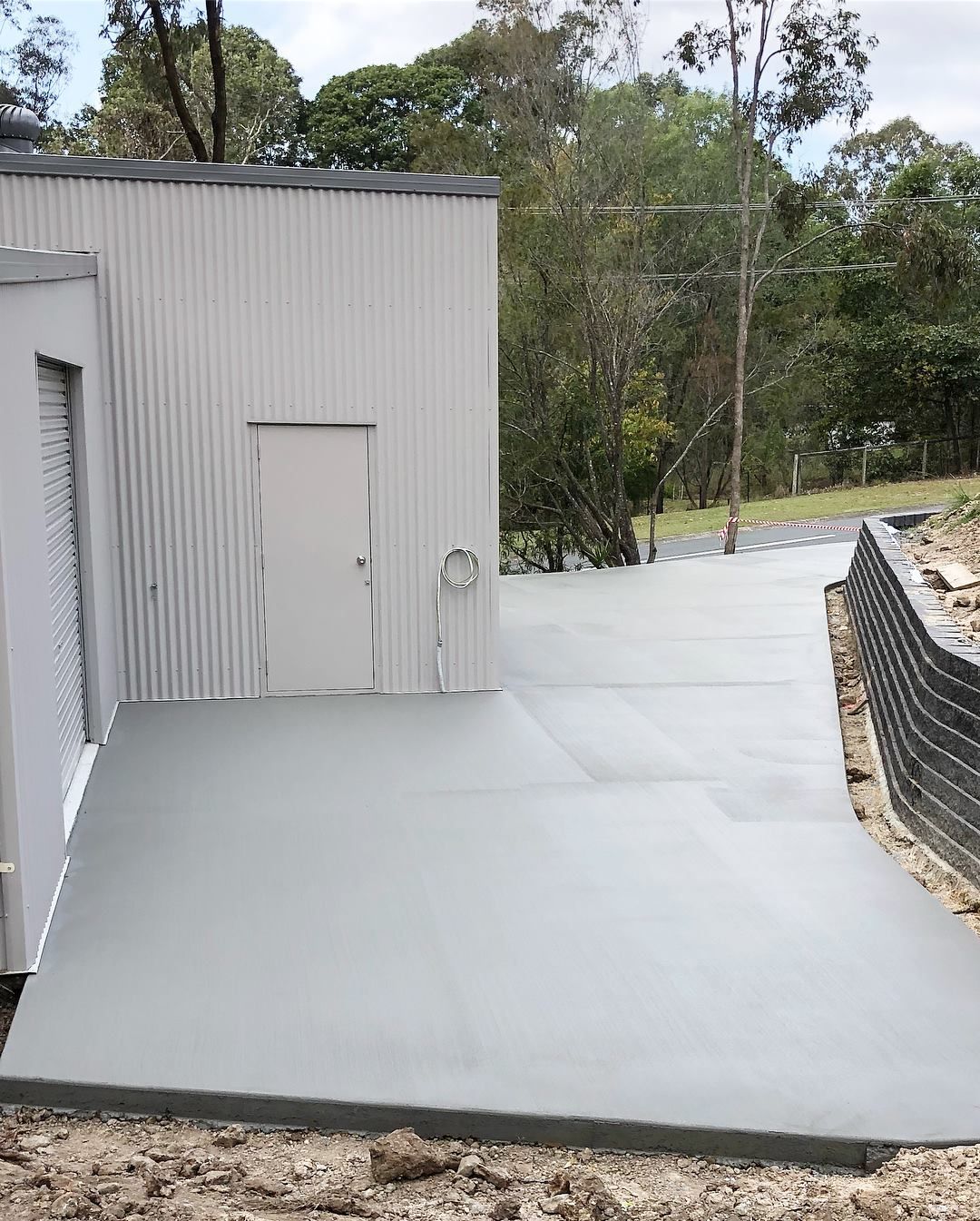 A Newly Poured Concrete Slab Next to a Light Gray Metal Shed — Sand & Stone in Mudgeeraba, QLD