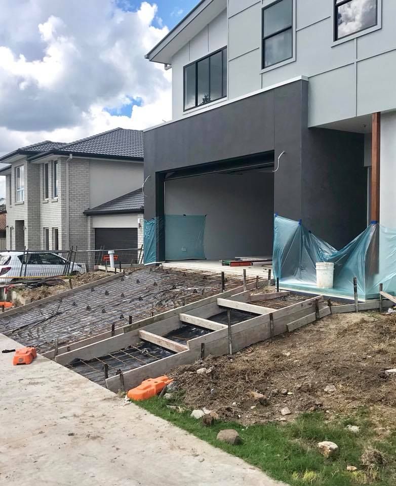 A house under construction with a sloping driveway and concrete stairs framed for pouring leading to the entrance. — Sand & Stone in Worongary, QLD