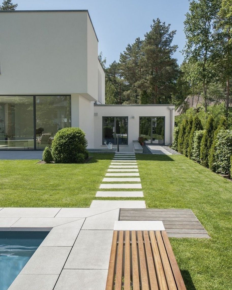 A modern white house with large windows, a swimming pool, and a stone walkway through a green lawn. — Sand & Stone in Worongary, QLD