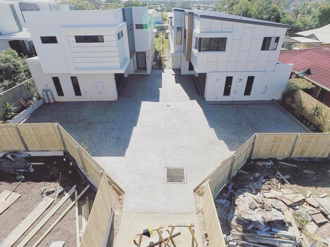 An aerial view of a paved driveway between two modern, two-story white houses under construction. — Sand & Stone in Worongary, QLD