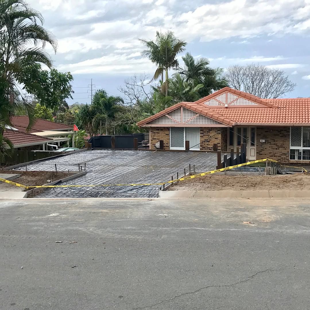 A residential property with a recently prepared concrete foundation enclosed by yellow caution tape. — Sand & Stone in Robina, QLD