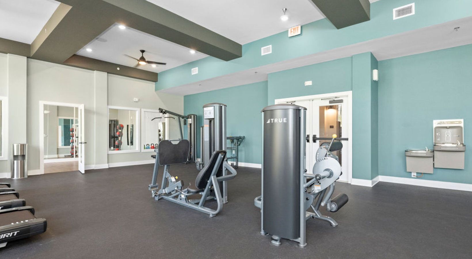 Gym with various exercise machines and a water fountain. We invite you to visit 1001 Tyvola and take a tour of our apartments with a fitness center in Mecklenburg County.