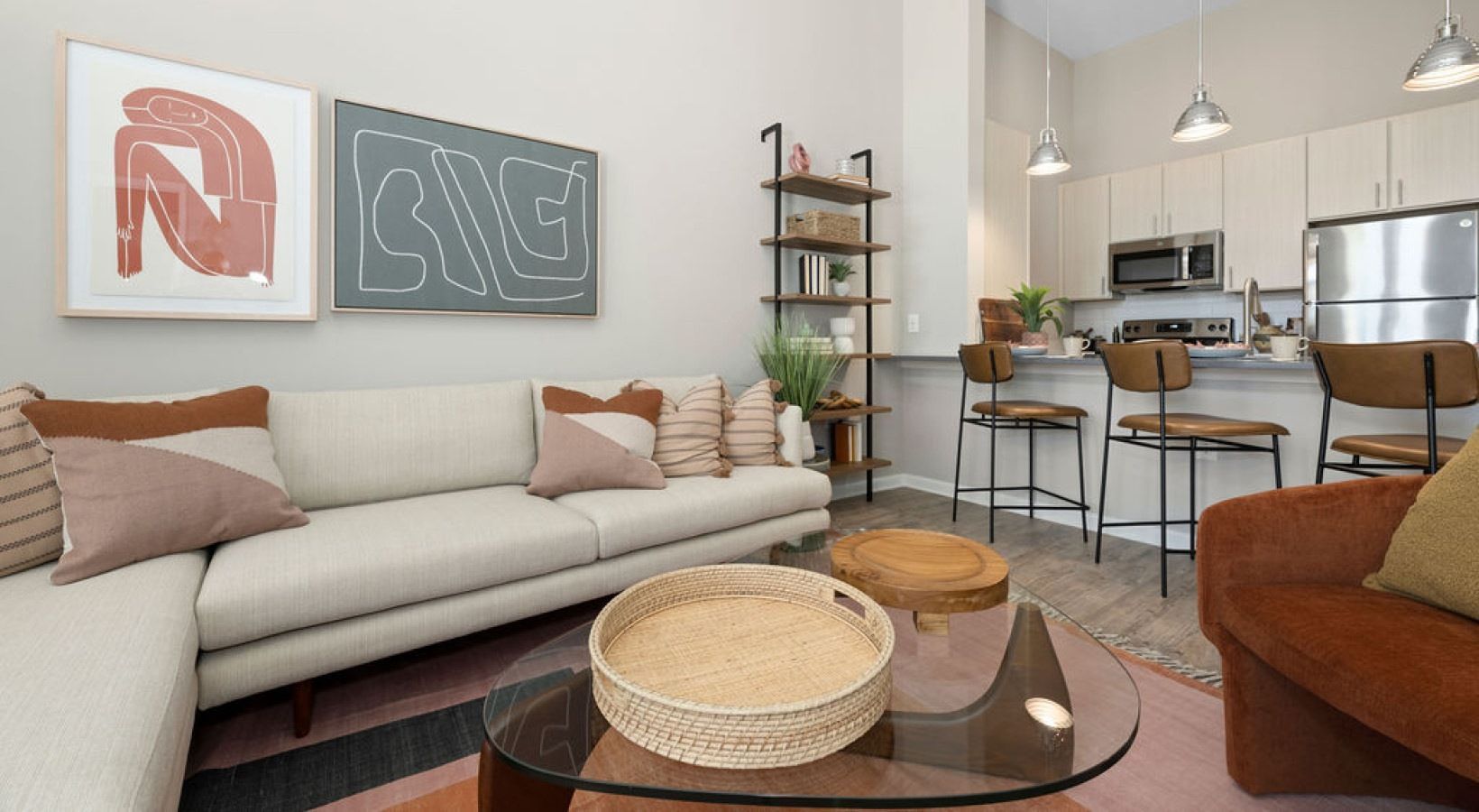 Living room with couch, art, open kitchen, bar stools. Neutral tones, natural light, modern décor. We invite you to visit 1001 Tyvola and take a tour of our apartments near Nations Ford Elementary in Charlotte.