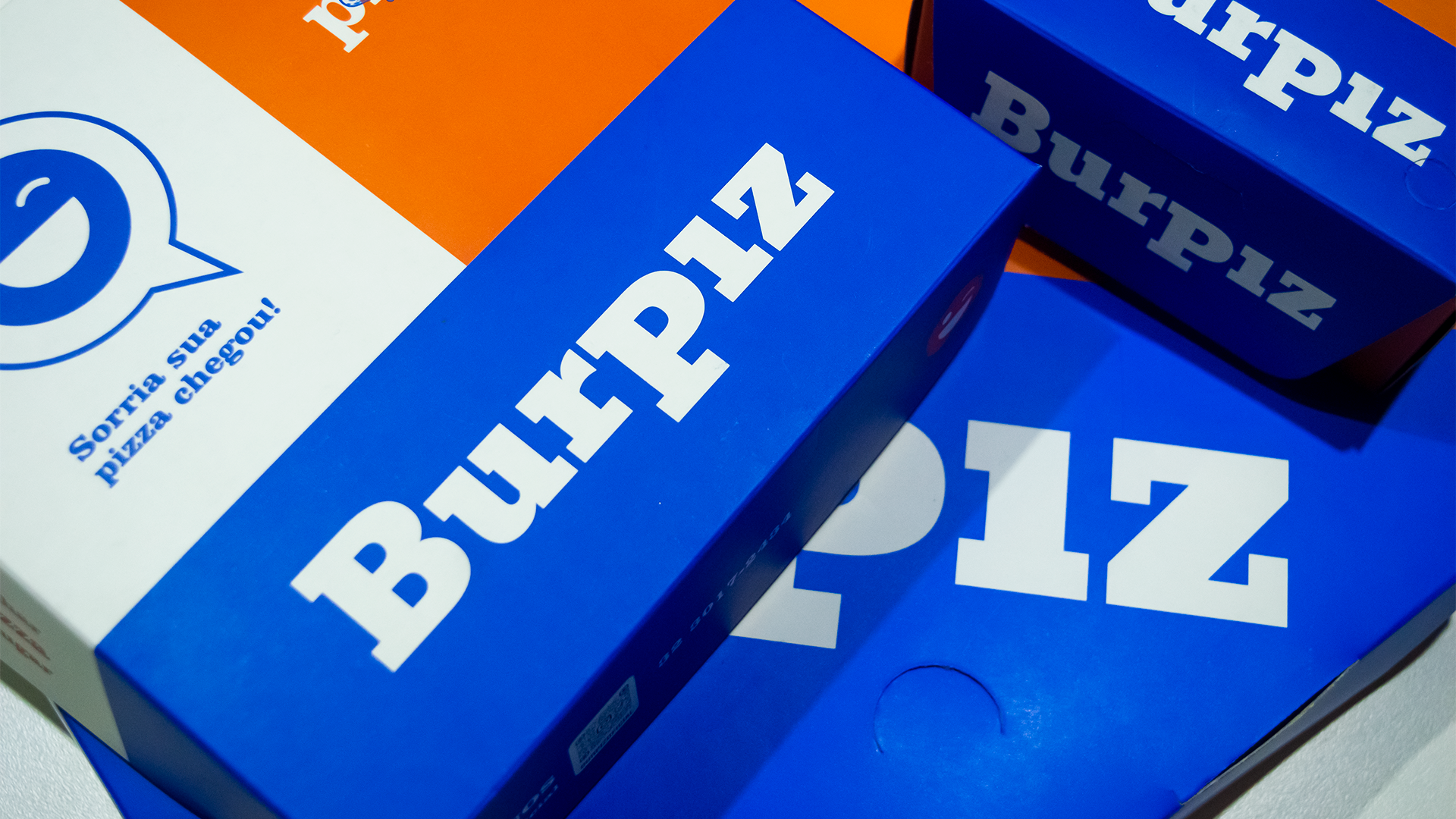Caixas de pizza Burpiz azuis e laranja.