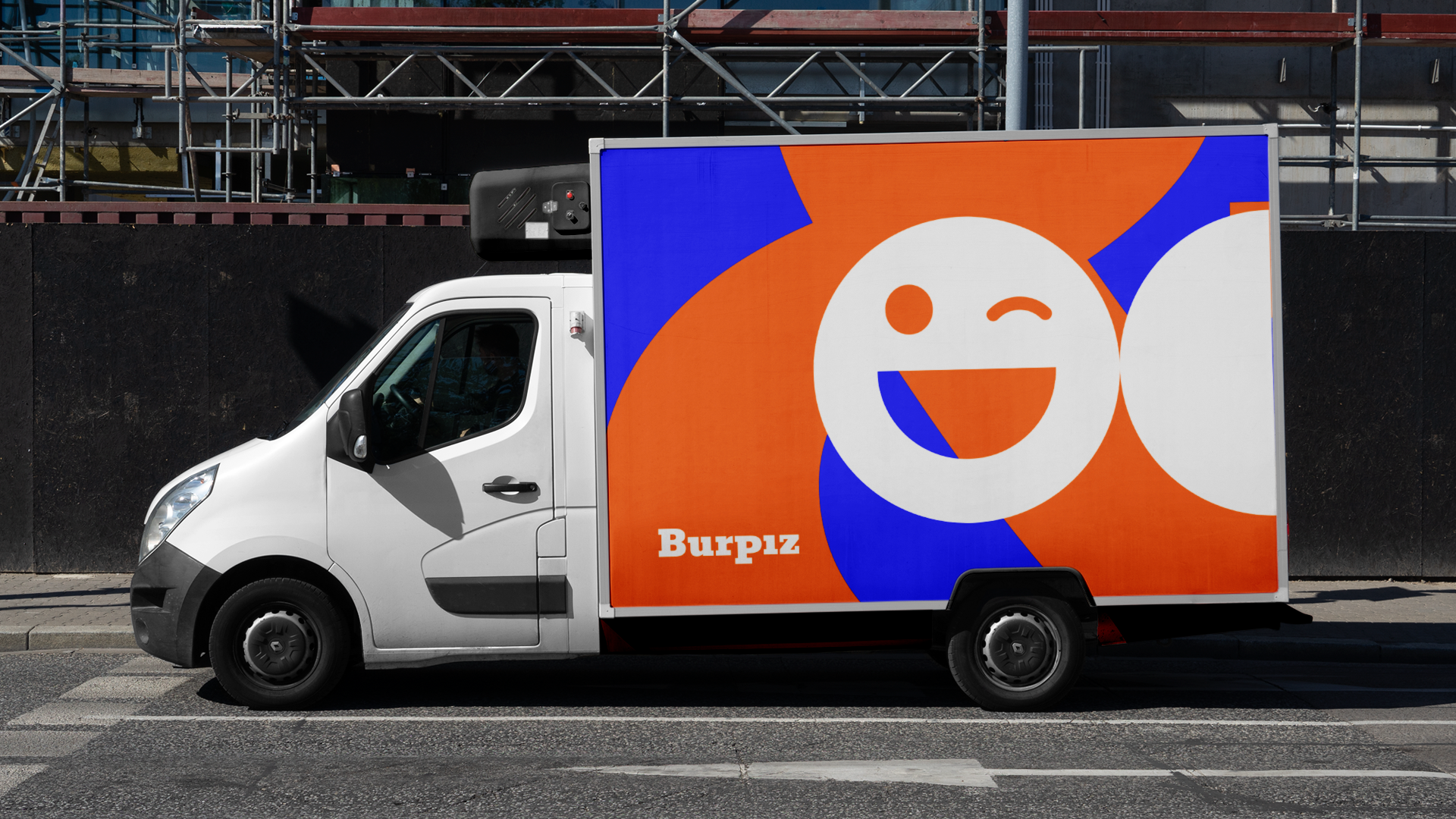 Caminhão de entrega branco com logotipo laranja e azul e um rosto sorridente na lateral; texto