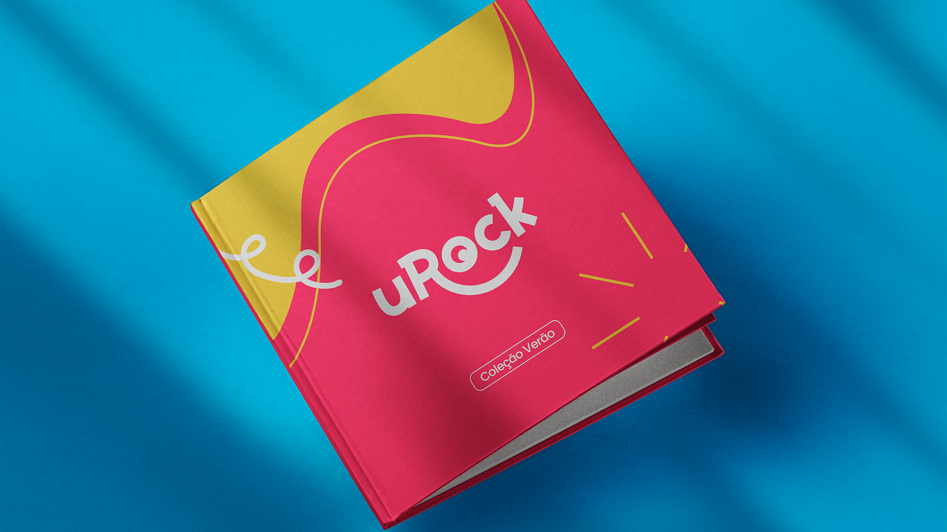 Um livro rosa e amarelo está sobre um pano azul.