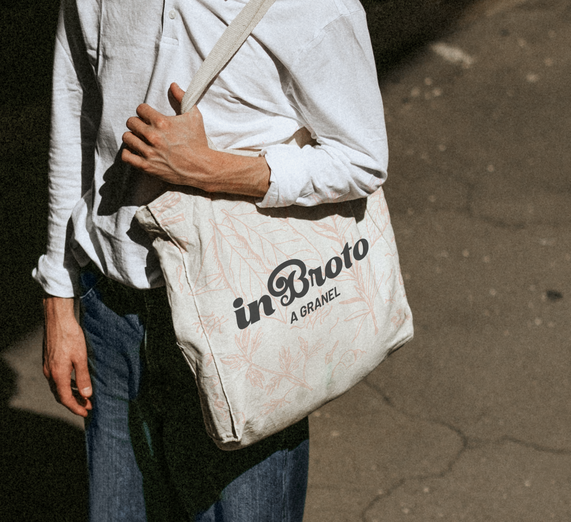 Pessoa vestindo camisa branca e jeans carrega uma bolsa bege com os dizeres
