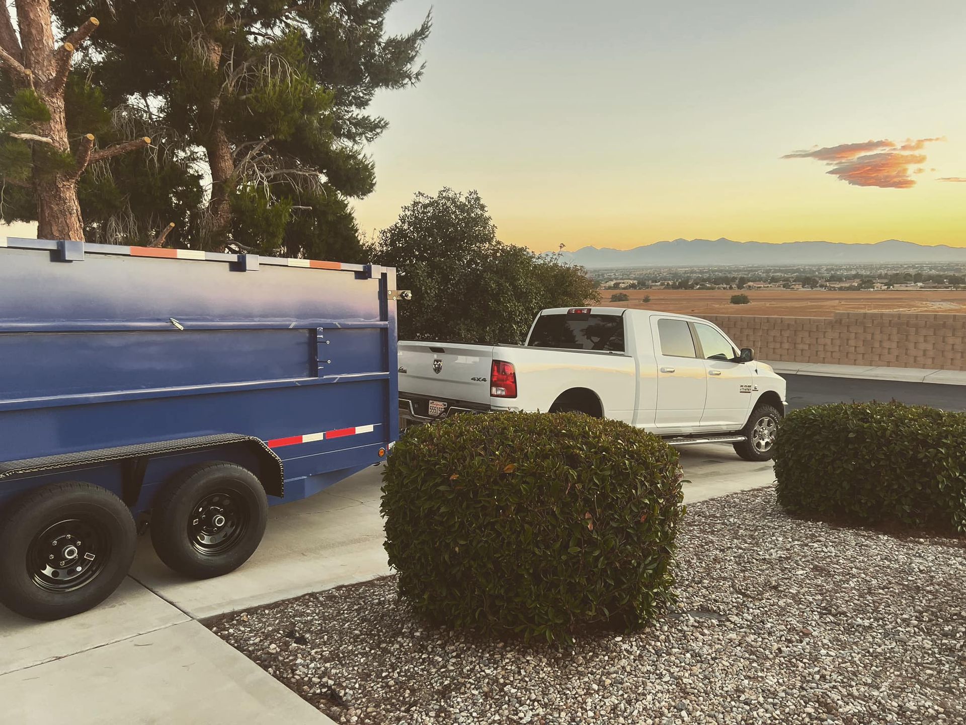 A white truck is parked next to a blue trailer