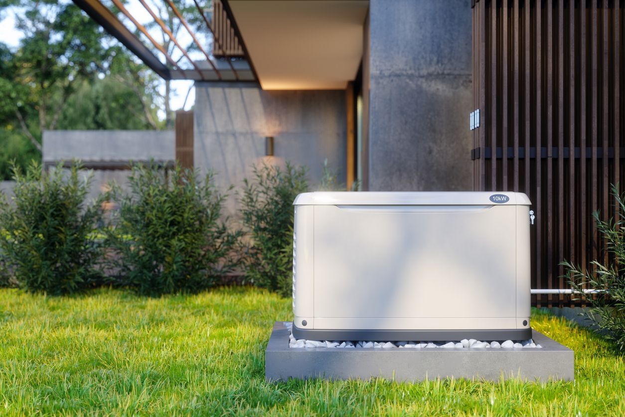 White outdoor generator on a gray base beside a modern house and green lawn