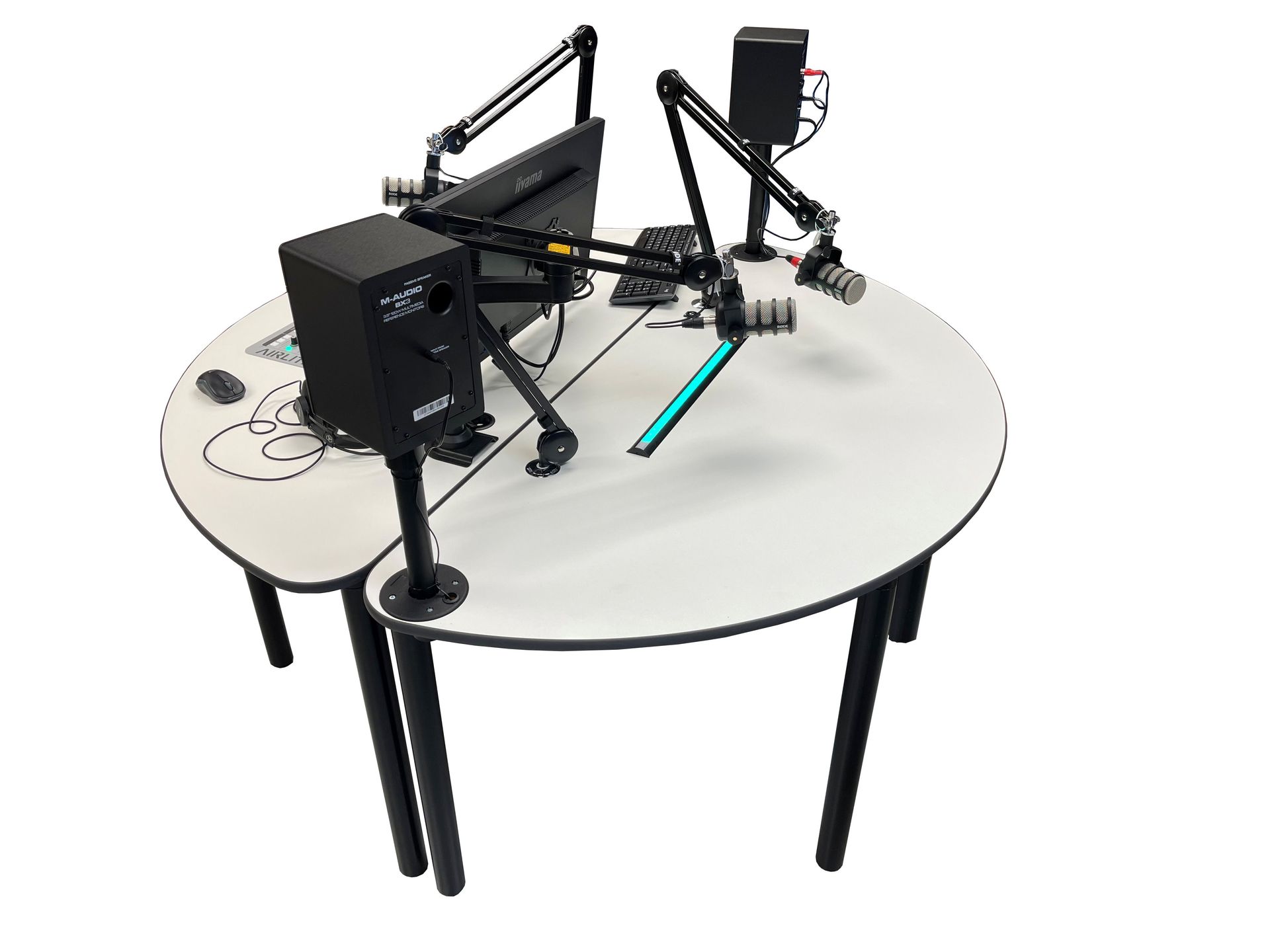 A round table with a computer , microphone , speakers and a monitor on it.
