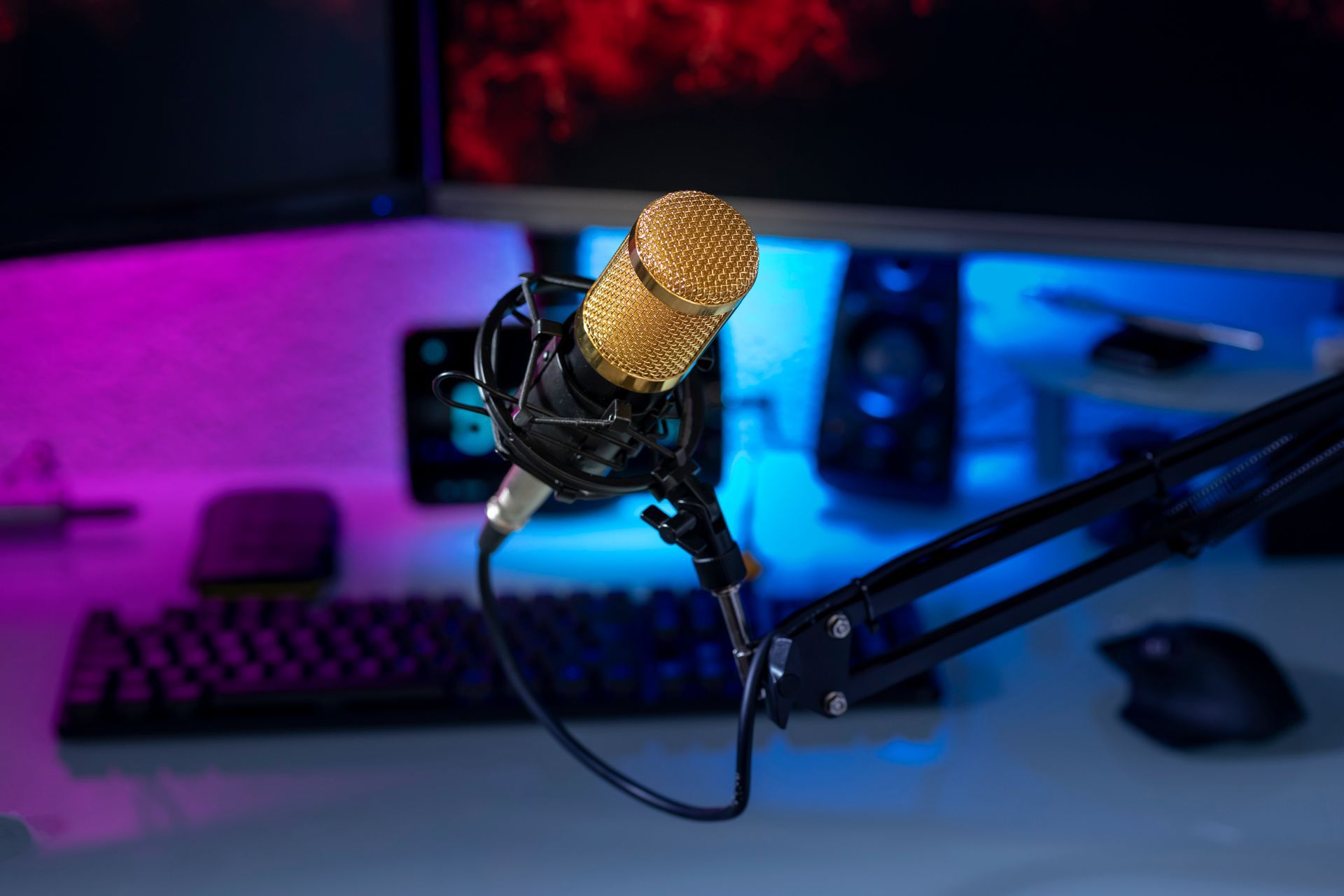 A microphone is sitting on a desk in front of a computer.