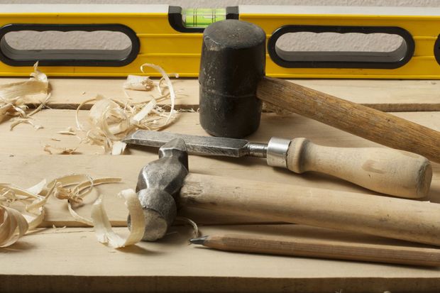 Attrezzi per la lavorazione del legno su un banco da lavoro con trucioli di legno e una livella a bolla gialla sullo sfondo.