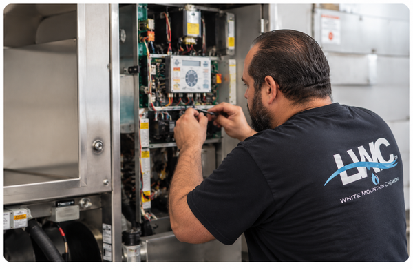 Technician repairs wiring inside an open electrical control cabinet.