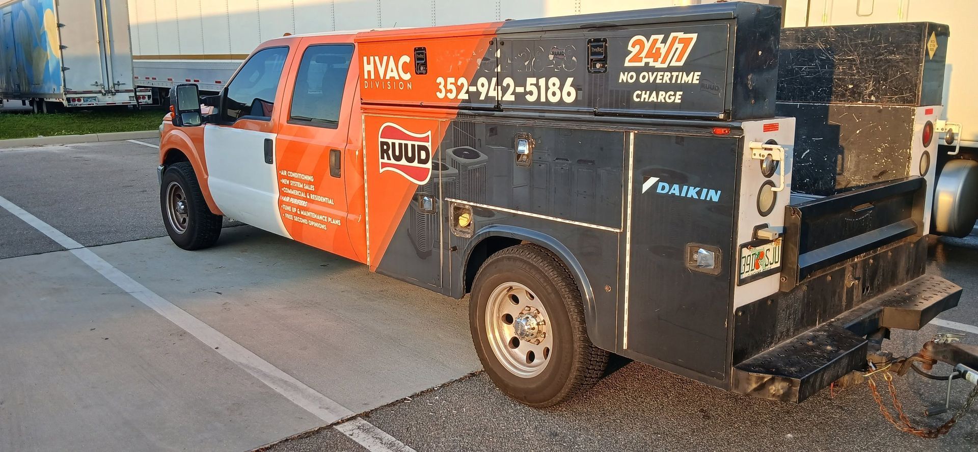 Orange-and-black service truck parked on a street, with company signage and equipment in the back.