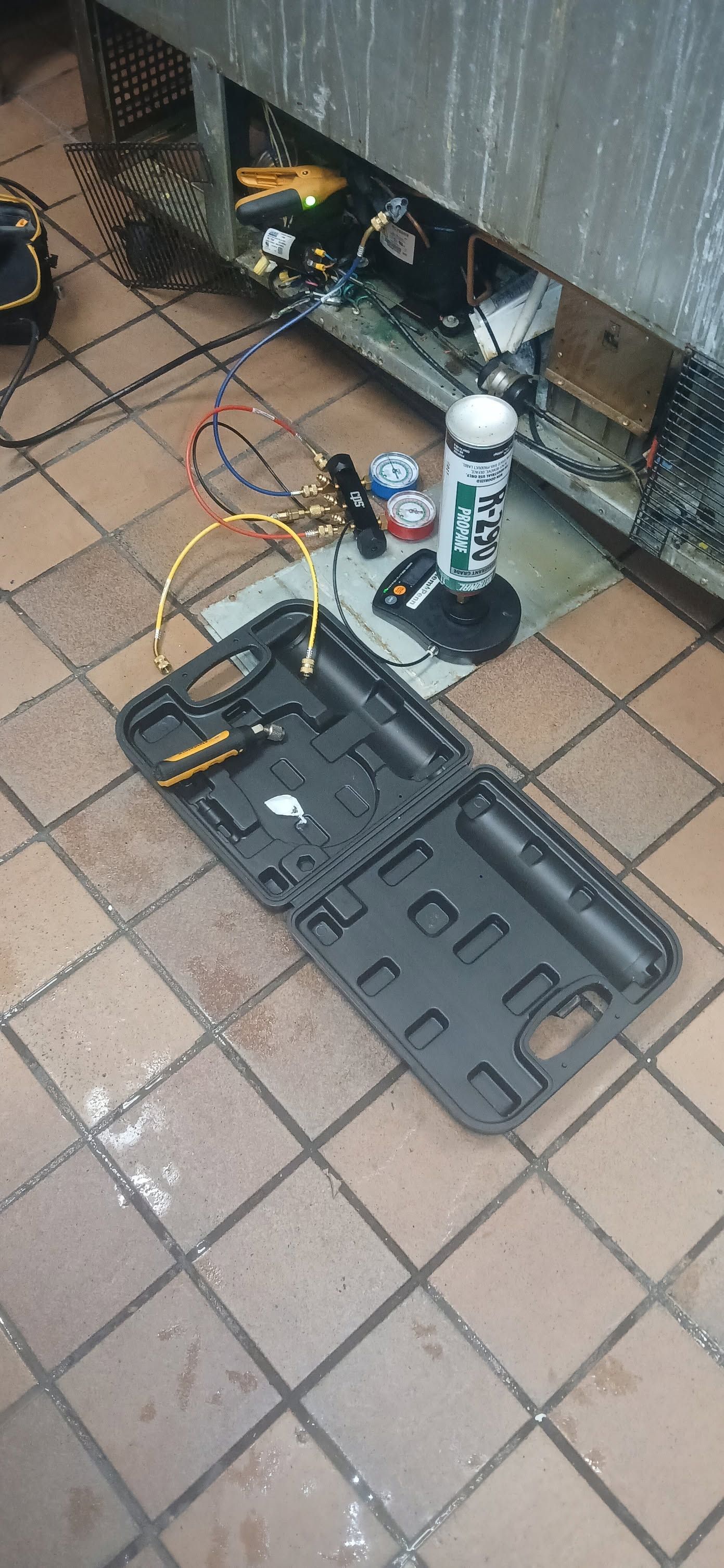 Tool case and small equipment spread on a tiled patio beside a metal fence.