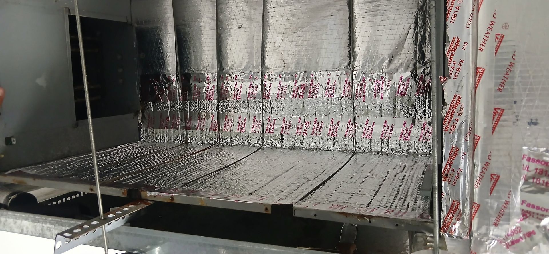 Metal interior with perforated floor and walls splattered with red residue.