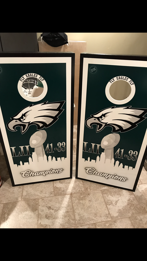 Two eagles cornhole boards are sitting on a tiled floor.