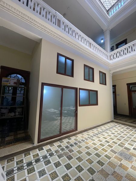 Patio luminoso con suelo de baldosas, paredes beige y múltiples ventanas bajo un techo alto con tragaluz.