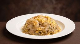 Plate of fried rice garnished with egg and herbs on a white dish against a dark background