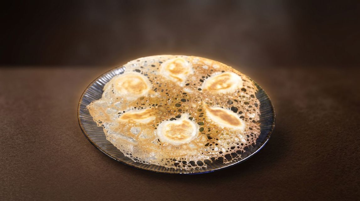 Bubbling fried food pieces in hot oil on a pan against a dark background