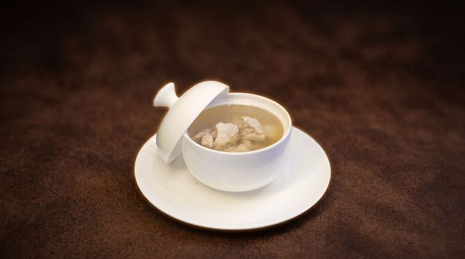 White cup of coffee on a saucer with a spoon, on a dark brown table.