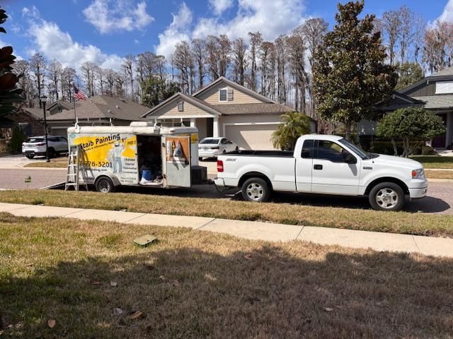 White pickup towing a yellow utility trailer in front of a suburban house on a sunny day