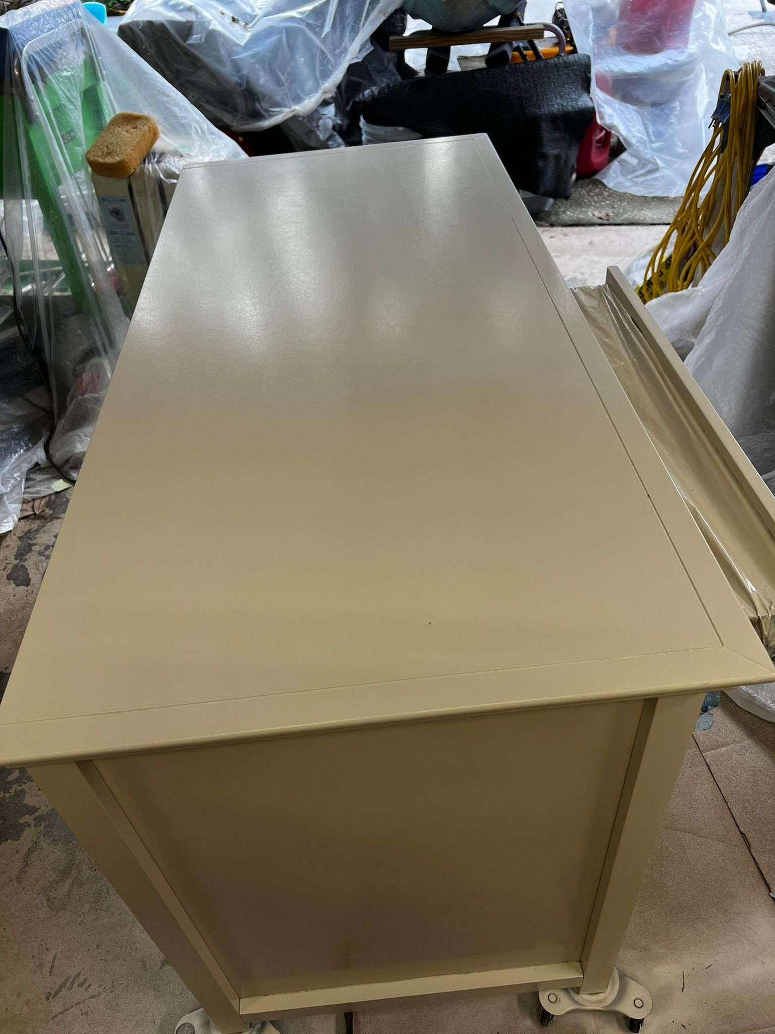 Beige metal filing cabinet with a flat top in a cluttered storage area