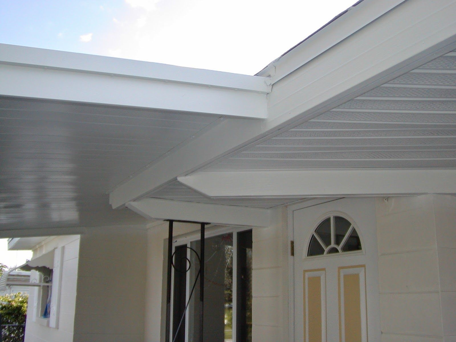 White house eaves and porch roof over a front door with arched window panels