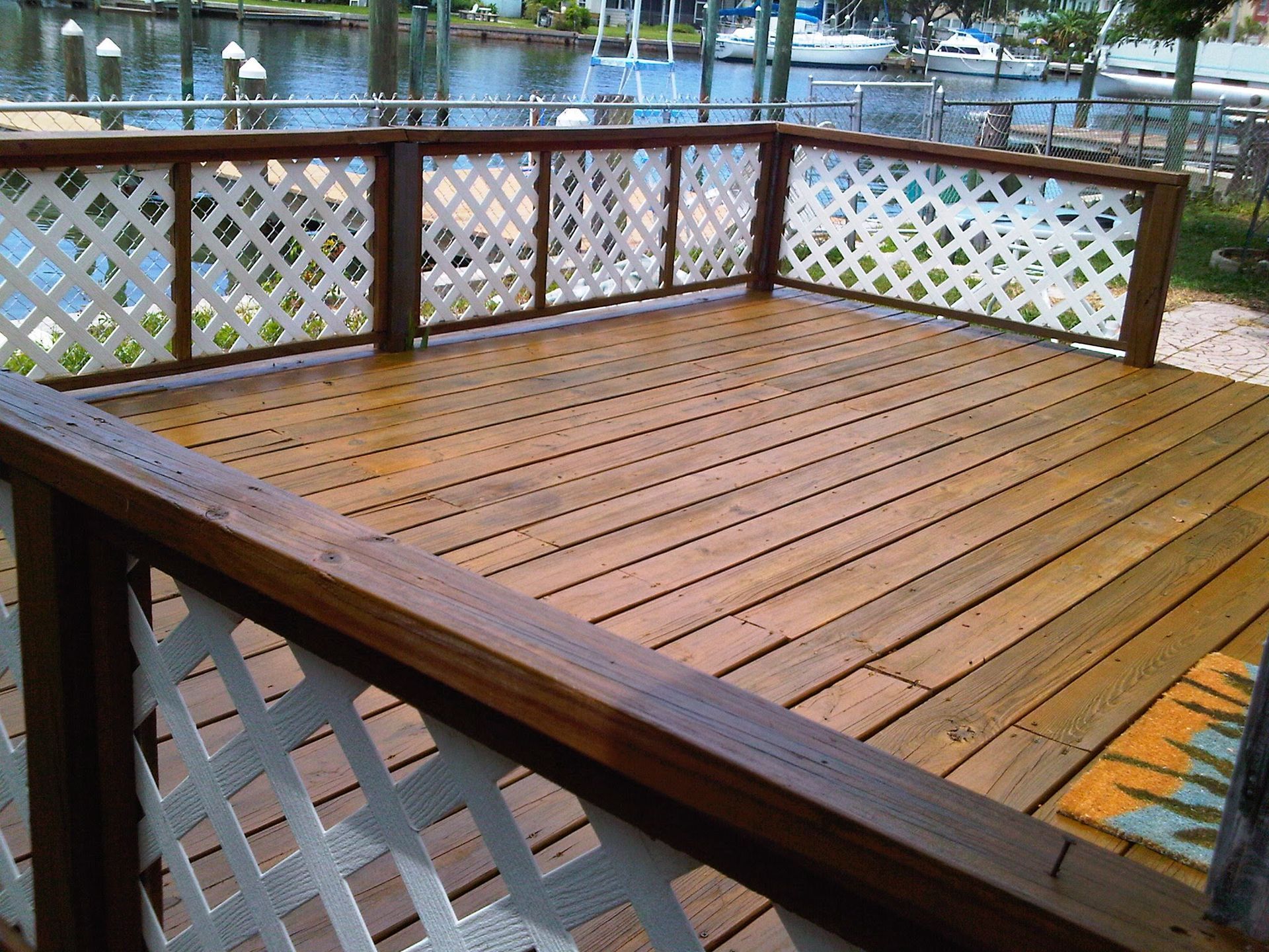 Wooden deck with lattice railing by the water, viewed from a corner.