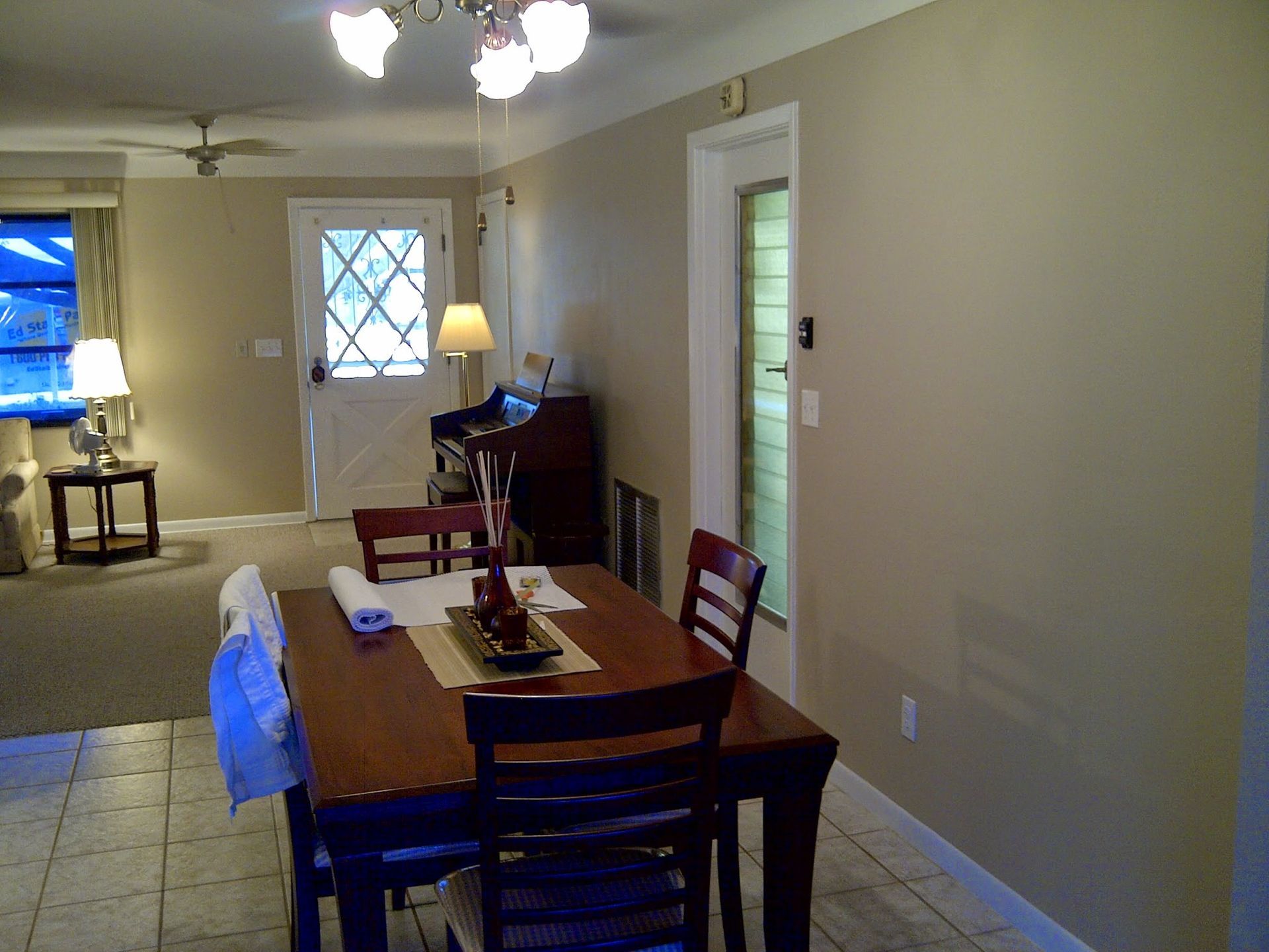 Dining room with table and chairs, beige walls, tiled floor, and a doorway to another room.