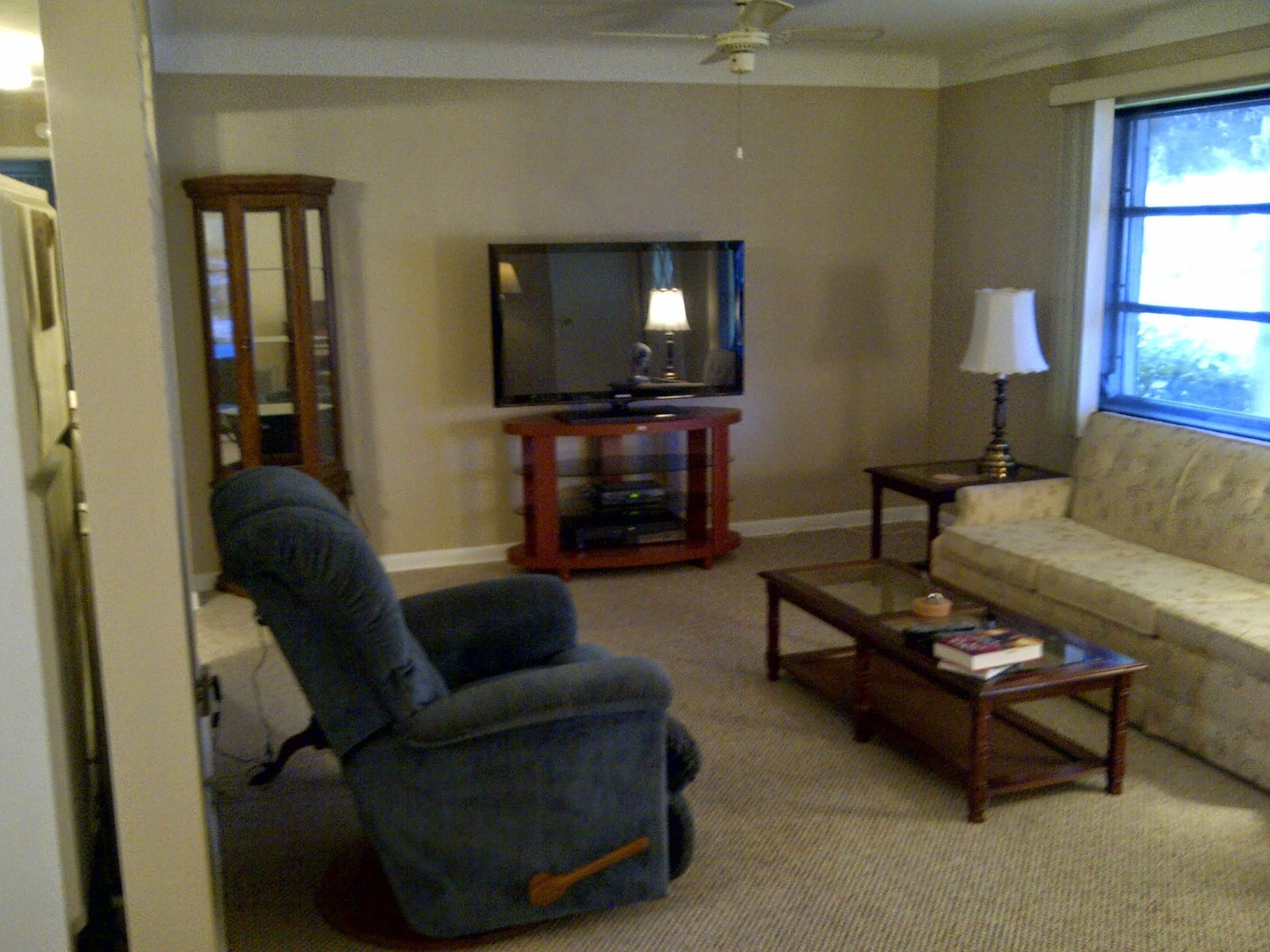 Living room with blue recliner, TV, sofa, coffee table, and lamp