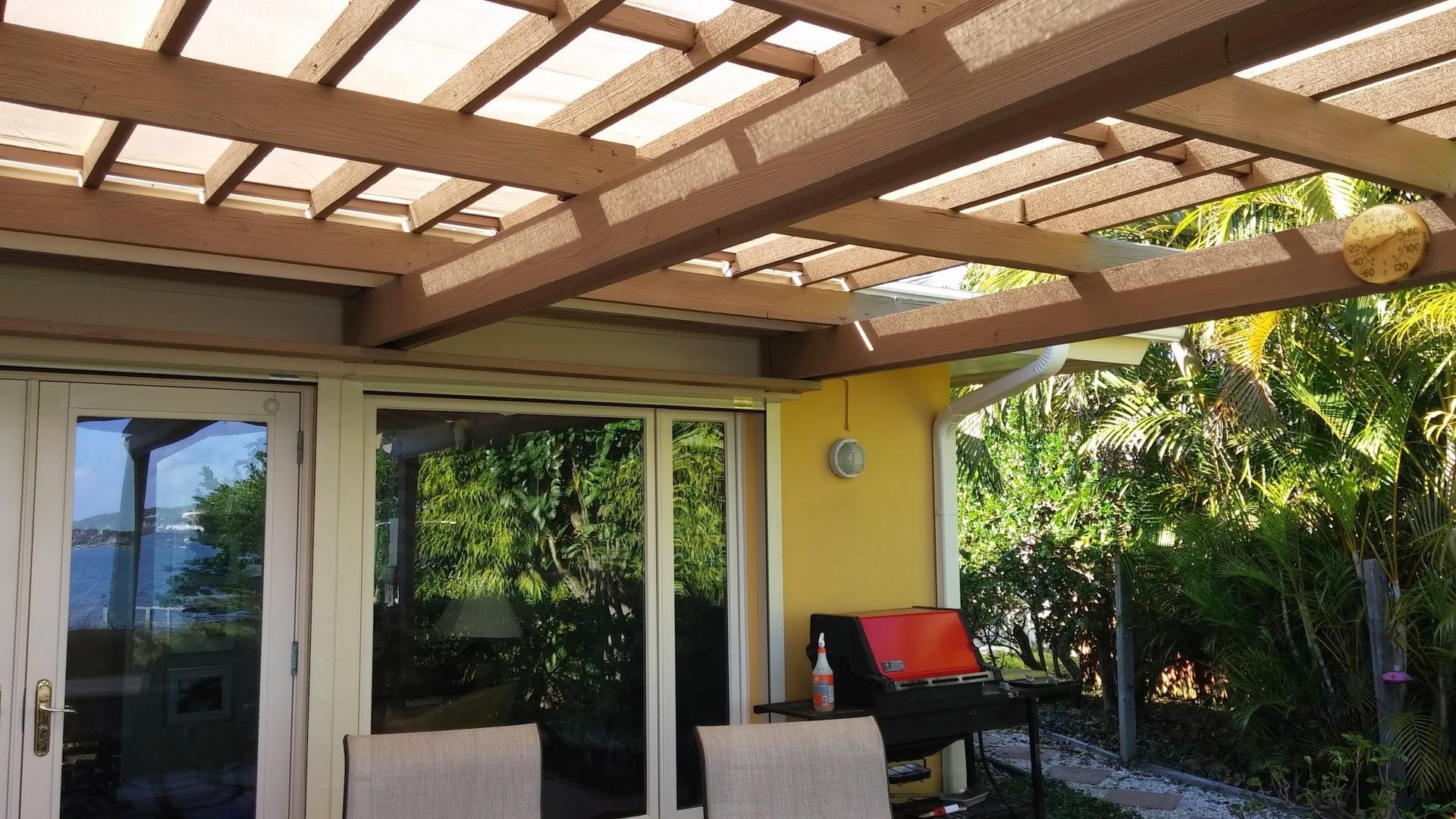 Patio with pergola roof, sliding glass doors, and outdoor seating beside lush green garden