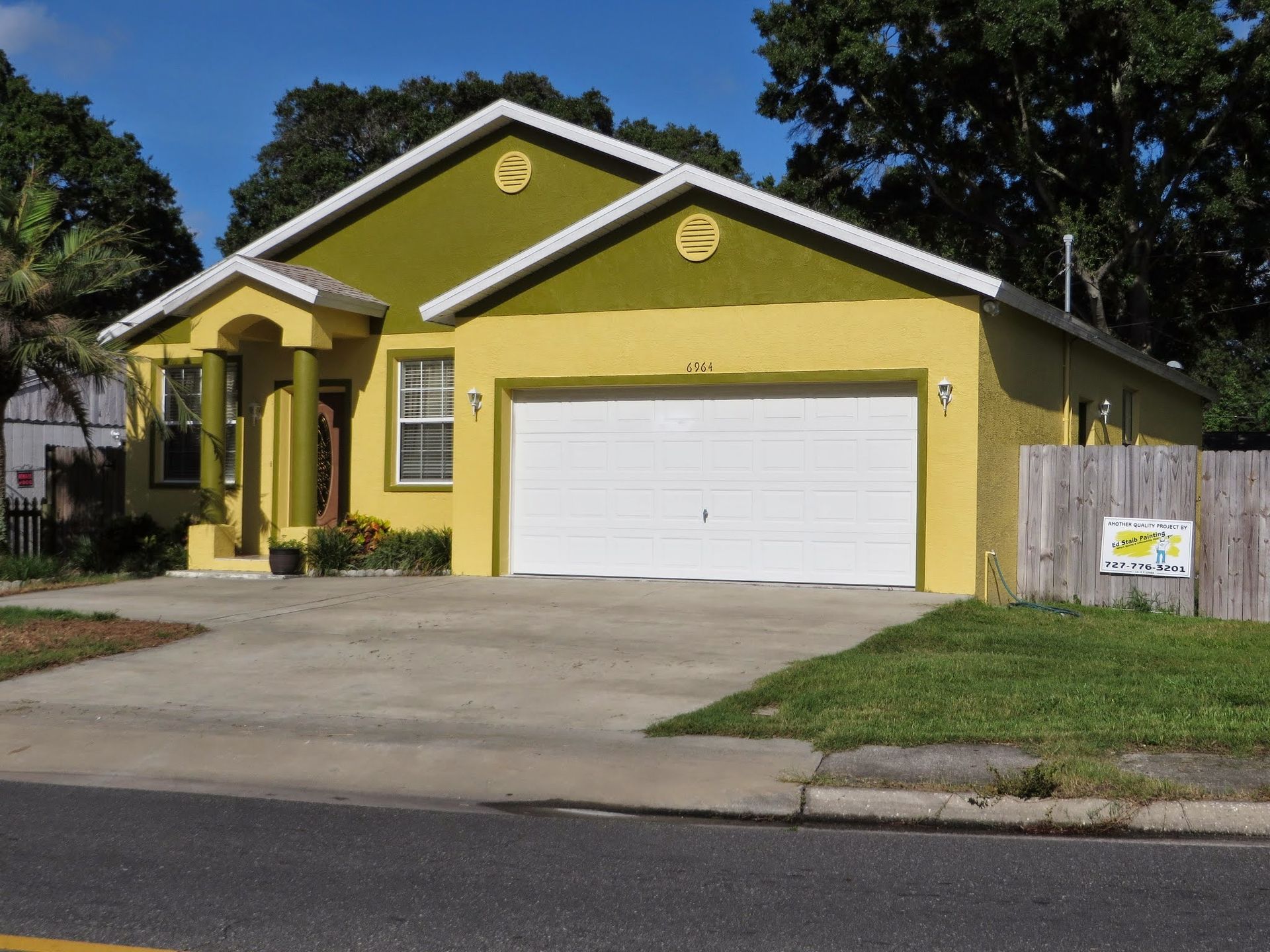 Yellow single-story house with white garage door and front lawn, viewed from the street