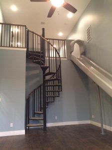 An empty room with a spiral staircase and a slide.