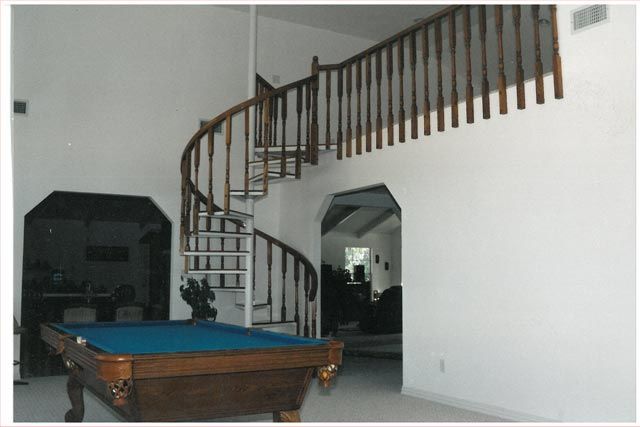A pool table in front of a spiral staircase
