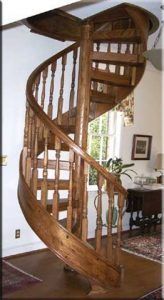 A wooden spiral staircase is in a living room.
