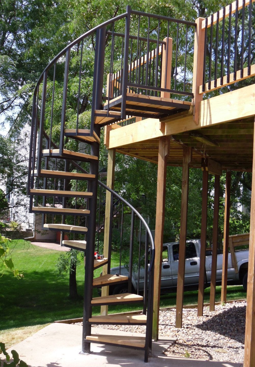 A wooden deck with a spiral staircase leading up to it